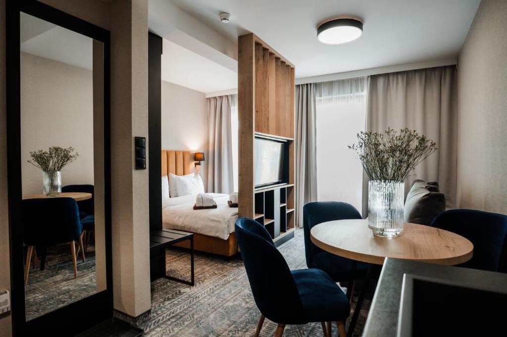 Modern hotel suite showing bed, wood partition, round dining table and blue chairs