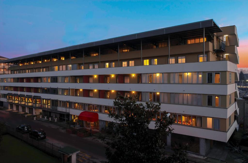 a large white building with many windows at dusk at Hotel La Bussola in Novara