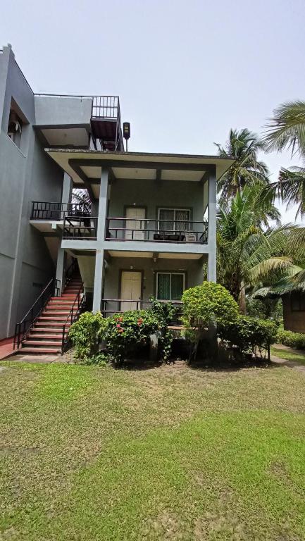 Santa MagdalenaSuki Beach Resort "D" Standard Aircon Room的带阳台和棕榈树的房子