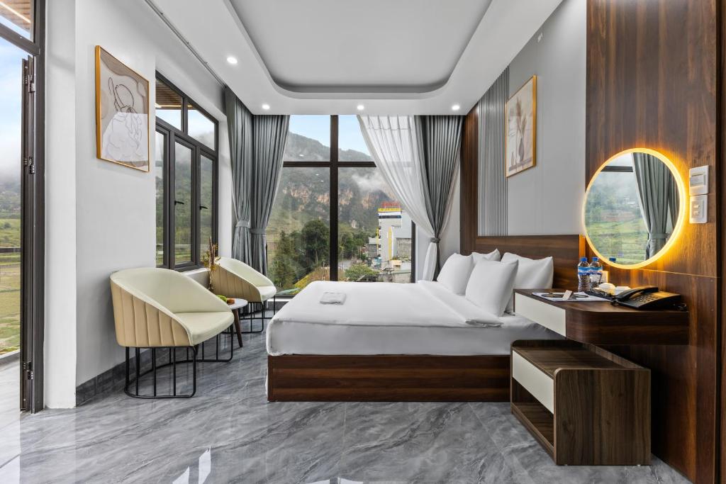 a hotel room with a bed and a desk and chairs at Ha Giang Hill Hotel in Dồng Văn