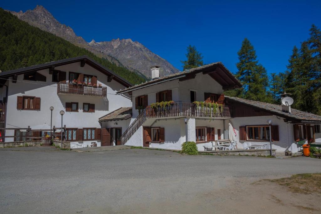 uma grande casa branca com uma montanha ao fundo em Hotel Camping Grivola em Valsavarenche