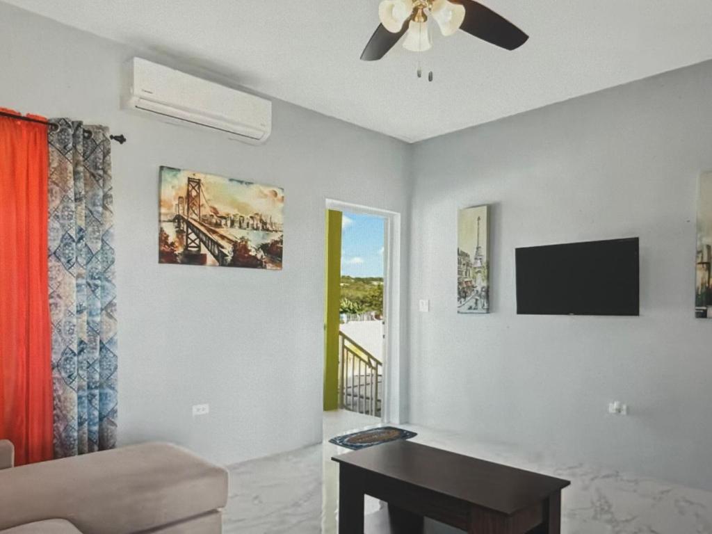 Una sala de estar con ventilador de techo y televisor. en Tropical paradise, 