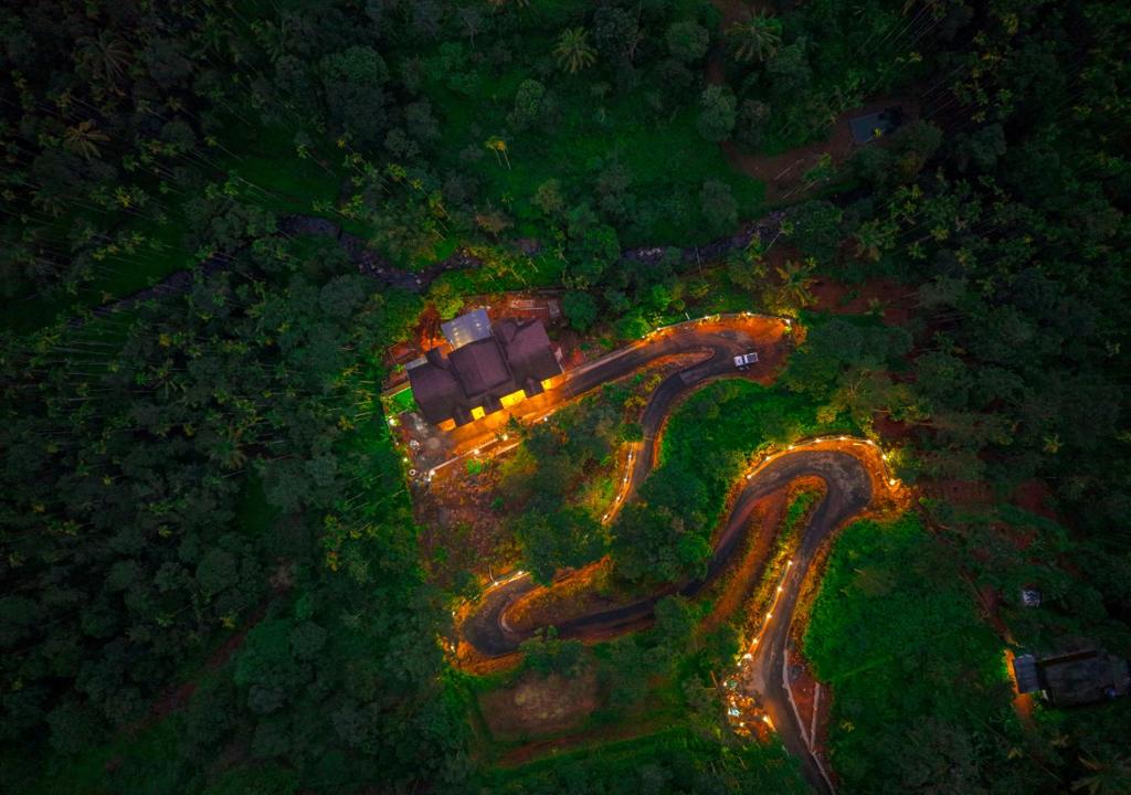 Achutham Cottages Wayanad by VOYE HOMES - Nature Luxe near Banasura Dam في Padinjarathara: منظر جوي لمنزل مع أضواء على الطريق