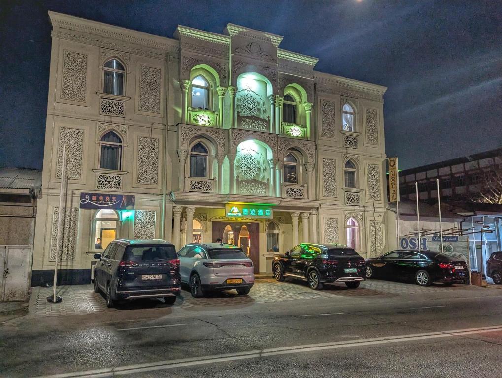 a building with cars parked in front of it at night at Moji Hotel Tashkent in Tashkent