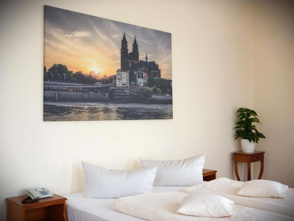 a bedroom with a bed with a picture on the wall at Mercure Hotel Plaza Magdeburg in Magdeburg