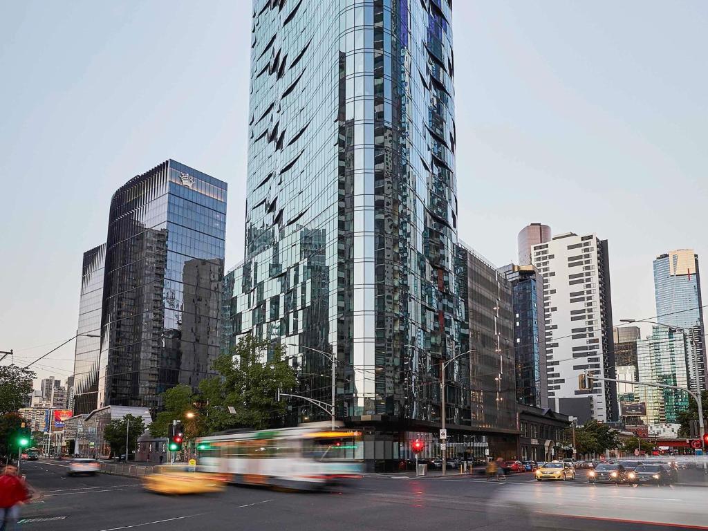 a tall glass building in a city with cars at Shadow Play by Peppers in Melbourne
