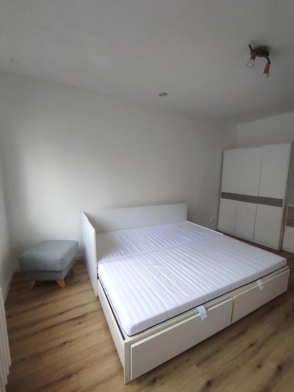 a bedroom with a white bed and a wooden floor at Moderný apartmán pri lesoparku in Košice