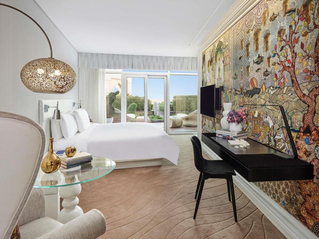 a hotel room with a bed and a desk with a desk at Mondrian Doha in Doha