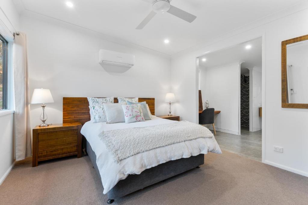 a white bedroom with a large bed and a mirror at Elizabeths House in Ballandean