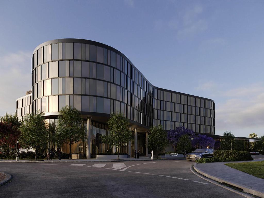 un grand bâtiment en verre avec une rue en face dans l'établissement Pullman Sydney Penrith, à Penrith