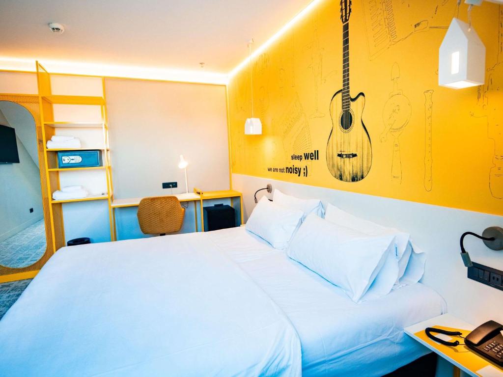 een slaapkamer met een bed en een gitaar aan de muur bij Ibis Styles Sibiu Arsenal in Sibiu