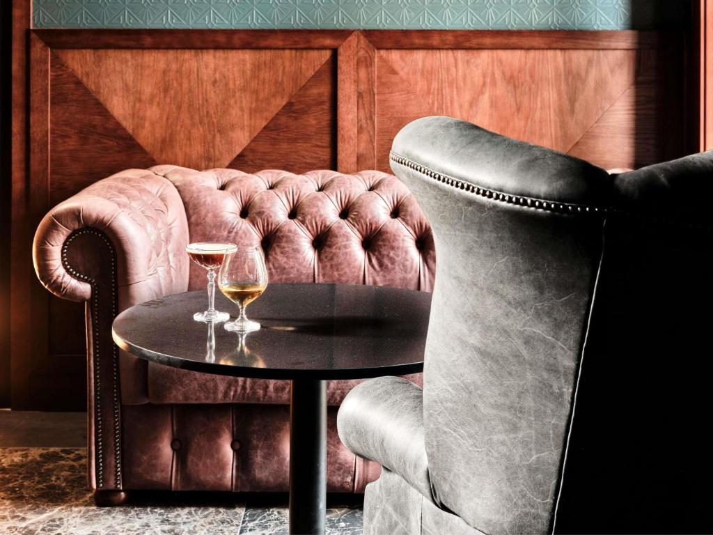 une table et une chaise avec deux verres de vin dans l'établissement The Crown Krakow Center - Handwritten Collection ACCOR, à Cracovie