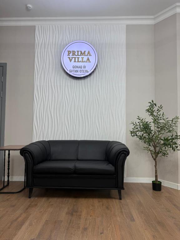 un canapé noir dans une pièce avec une pancarte sur le mur dans l'établissement Prima Villa Boutique Hotel отель, à Semey
