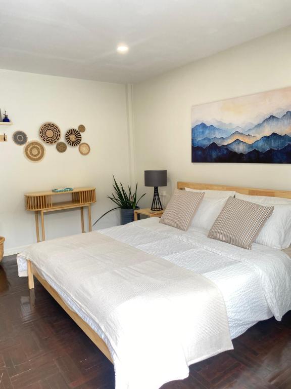une chambre avec un lit blanc et un tableau au mur dans l'établissement Central Nakhon Pathom 2BR Townhouse with AC & Kitchen, à Nakhon Pathom