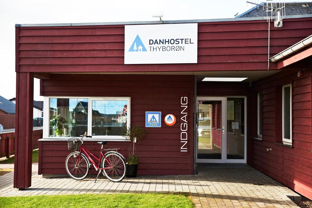 ein rotes Gebäude mit einem Fahrrad, das draußen geparkt ist in der Unterkunft Danhostel Thyborøn in Thyborøn