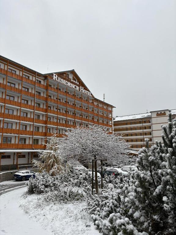 a snow covered tree in front of a hotel at Residence Hotel in Donovaly