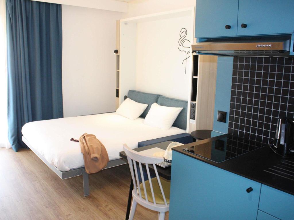 a small room with a bed and a desk with a chair at Aparthotel Adagio Access Porte de Camargue in Saint-Martin-de-Crau
