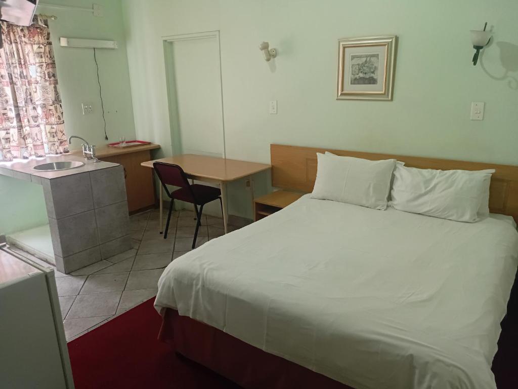 una camera da letto con un letto, un tavolo e un lavandino di Brackendene Lodge a Gaborone
