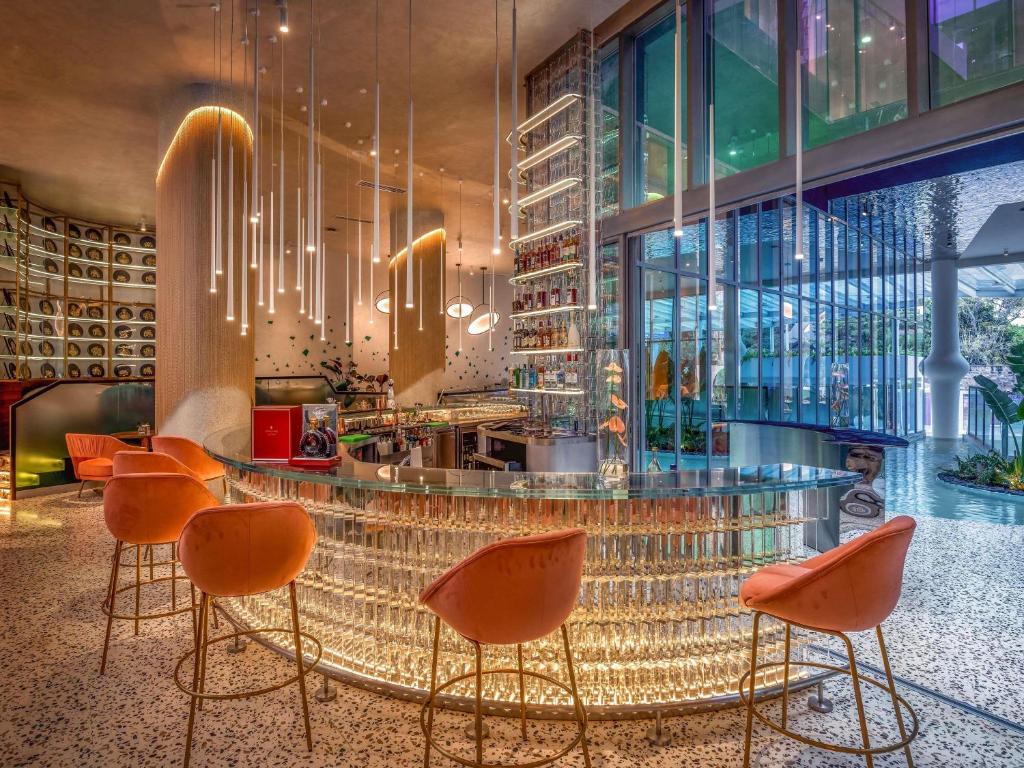 Un restaurante con sillas naranjas y un bar con mostrador de cristal. en Gem Forest Hotel Nairobi - MGallery Collection, en Nairobi