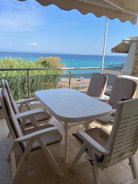 a table and chairs on a balcony with the ocean at Beachfront Bliss Polychrono in Polychrono