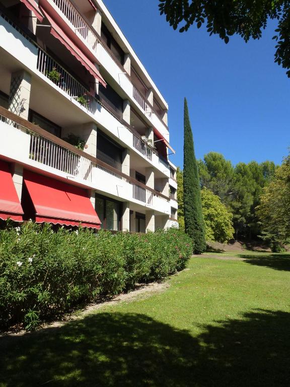 un bâtiment avec des auvents rouges et une cour verdoyante dans l'établissement Apartment Les Muriers Blancs, à Aix-en-Provence