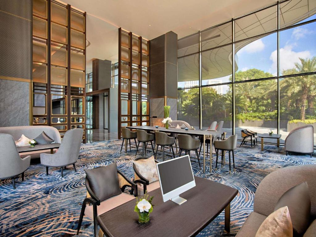 a hotel lobby with tables and chairs and windows at Pullman Hai Phong Grand Hotel in Hai Phong