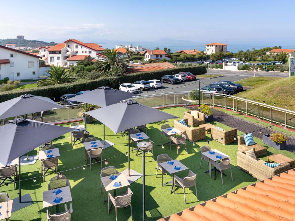 Una vista aérea de mesas y sillas con sombrillas. en ibis Styles Biarritz Plage, en Biarritz