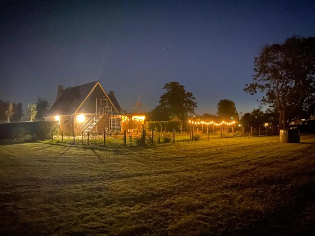 a barn with lights in a field at night at Appartement de 3 haasjes in landelijke omgeving. in Wijdenes