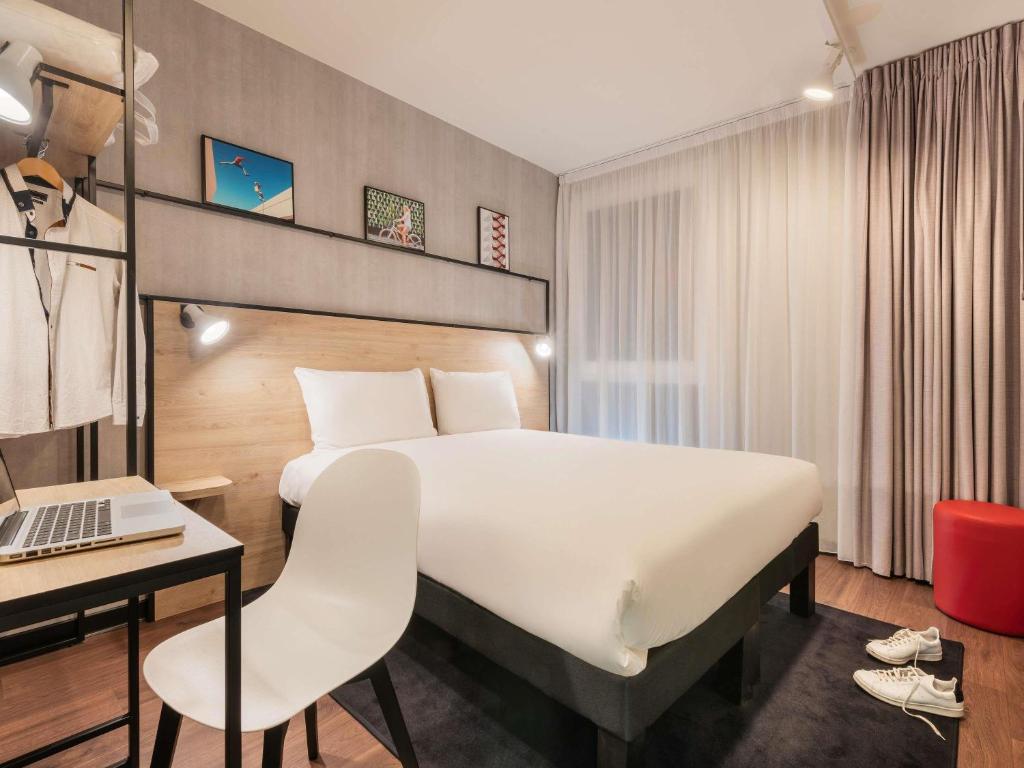 a hotel room with a bed and a desk and a laptop at ibis Acheres St Germain en Laye in Achères
