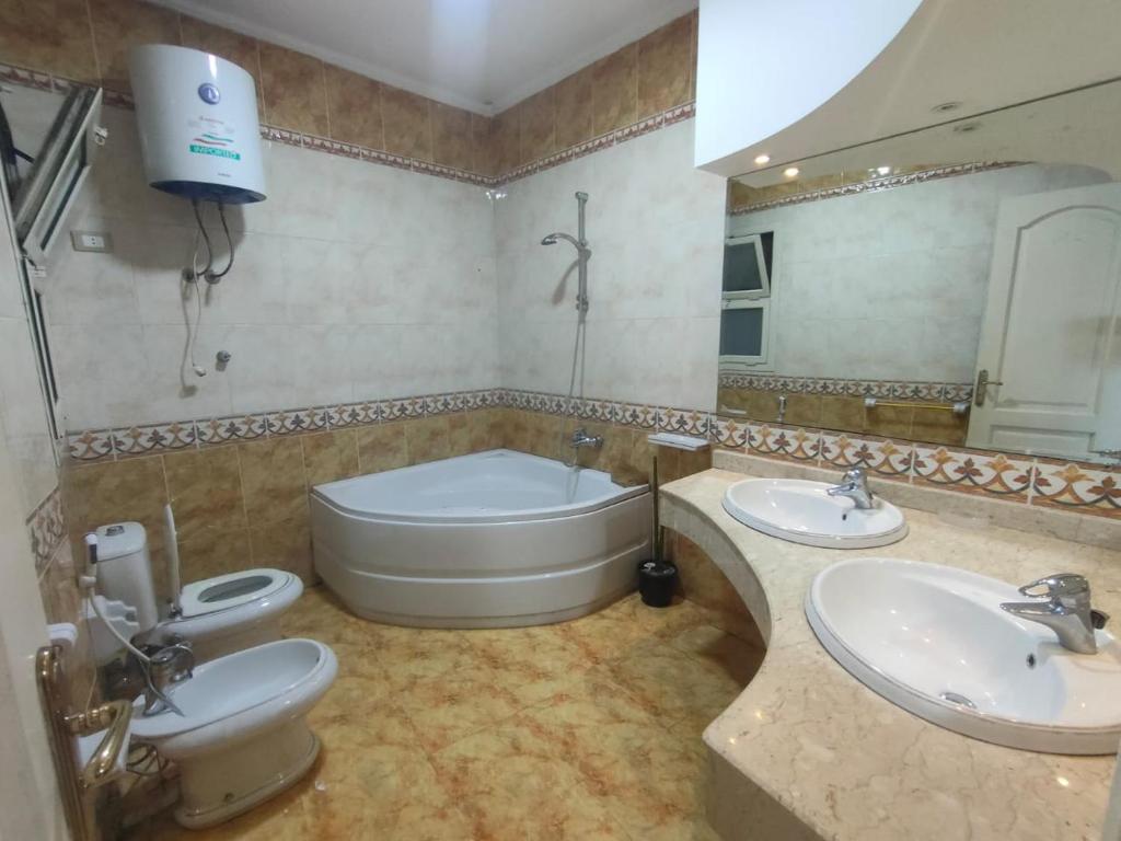 ein Badezimmer mit zwei Waschbecken und einer Badewanne und einer Toilette in der Unterkunft سبورتنج 5 in Alexandria