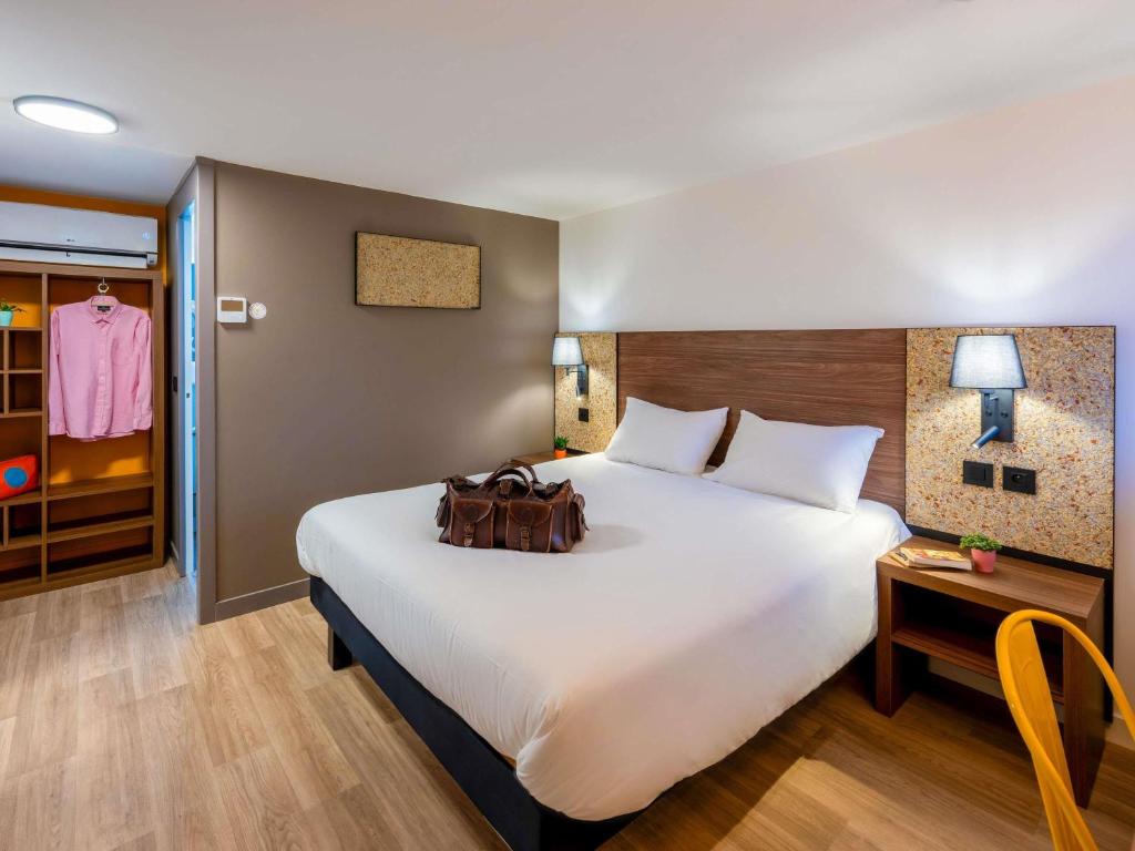 a hotel room with a large white bed and a table at greet Hotel Chatellerault in Châtellerault