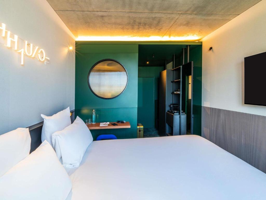 a bedroom with a large white bed and a mirror at TRIBE Paris Clichy in Clichy