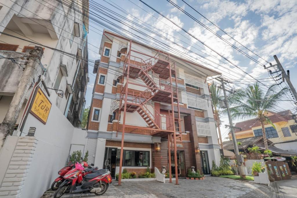 czerwony motocykl zaparkowany przed budynkiem w obiekcie TJR Boutique hotel w mieście Chiang Mai