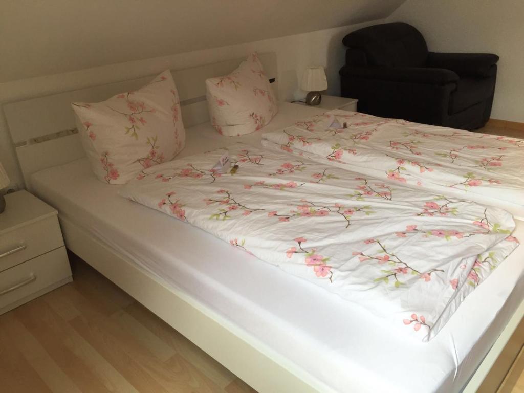 ein weißes Bett mit rosa Blumen drauf in der Unterkunft Fewo Zur Ilmenau in Melbeck