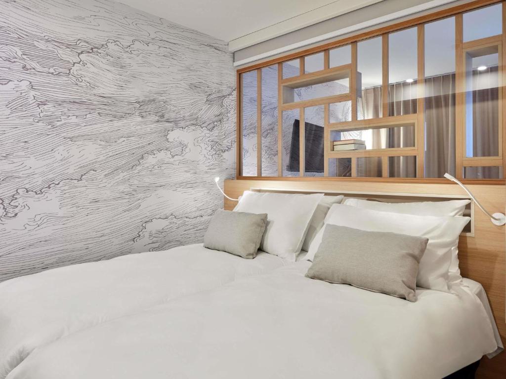 a white bed with two pillows in a bedroom at Aparthotel Adagio Stuttgart NeckarPark in Stuttgart
