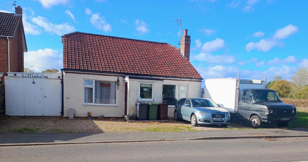 a truck and a car parked in front of a house at Littleholme in Potter Heigham