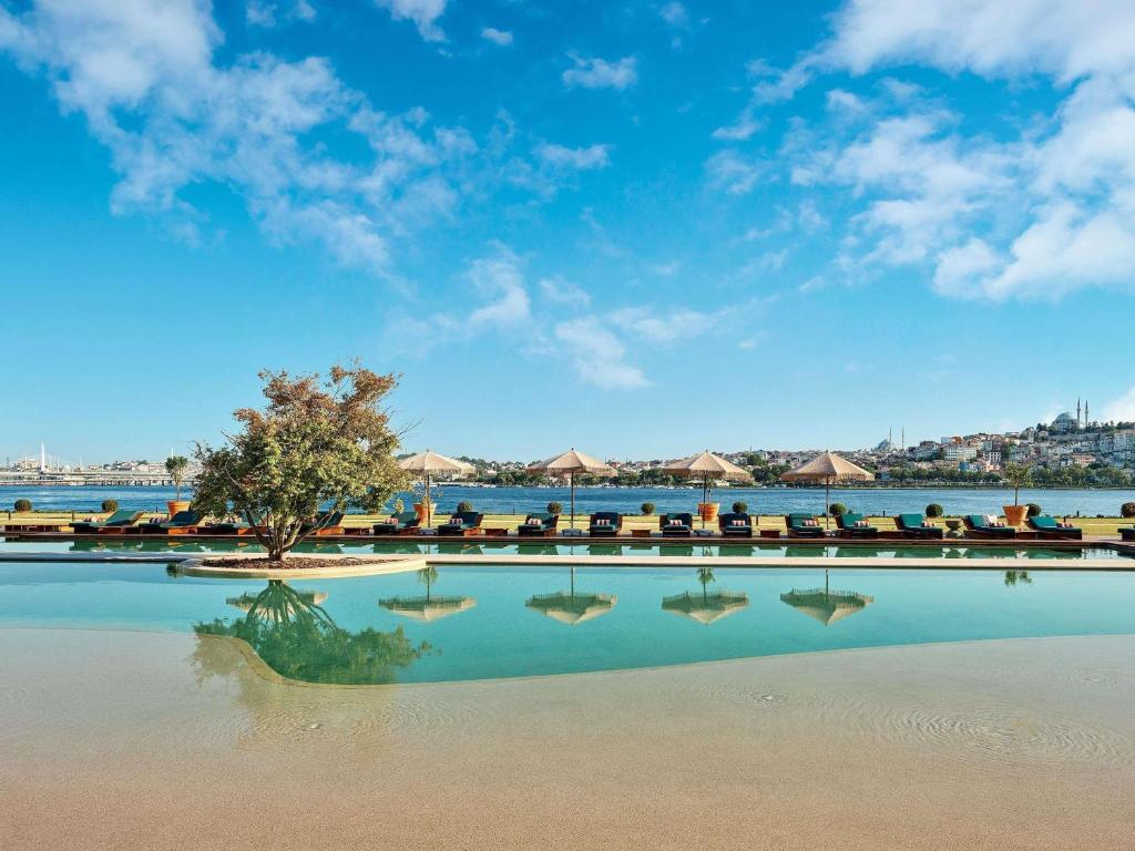 una piscina de agua con sillas y un árbol en Aliée Istanbul - A Paris Society Collection Hotel, en Estambul