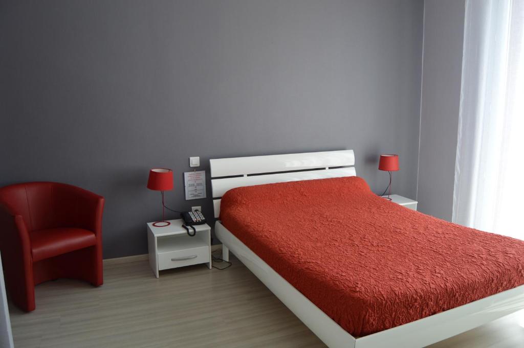 a bedroom with a red bed and a red chair at Hôtel Restaurant Le Bellevue in Ax-les-Thermes