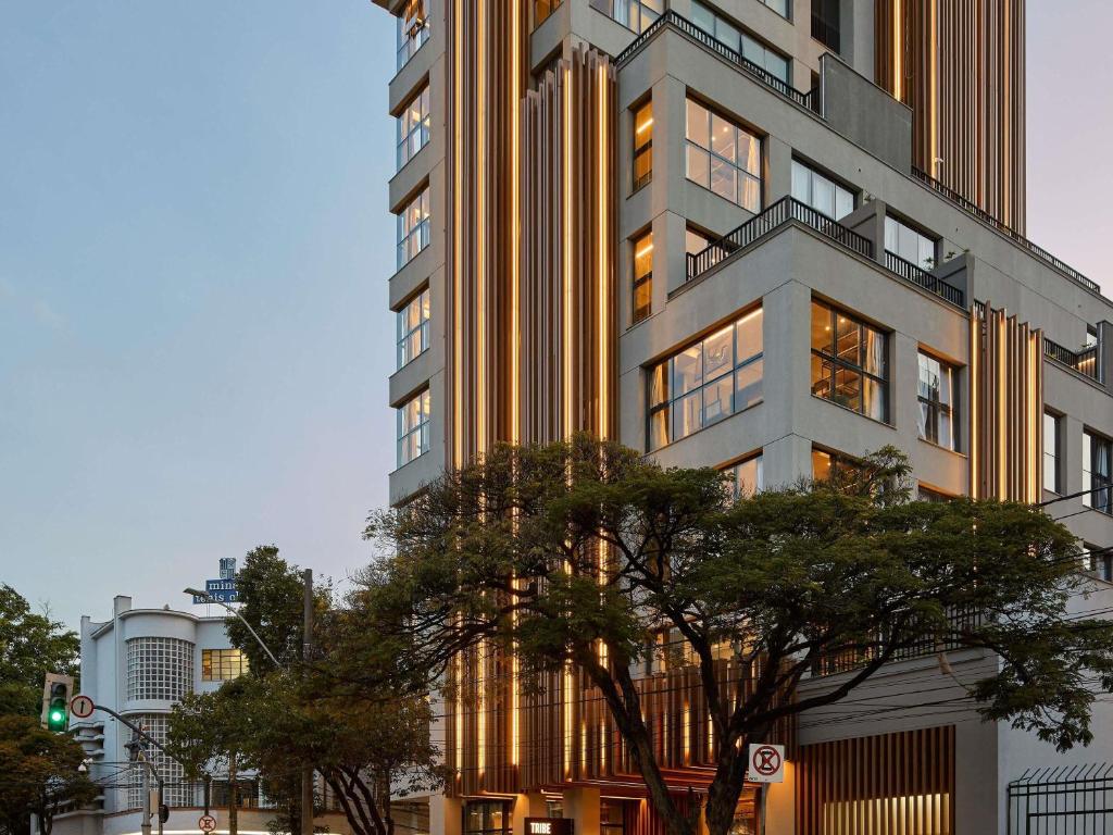 ein hohes Gebäude mit Bäumen davor in der Unterkunft TRIBE Belo Horizonte Savassi in Belo Horizonte