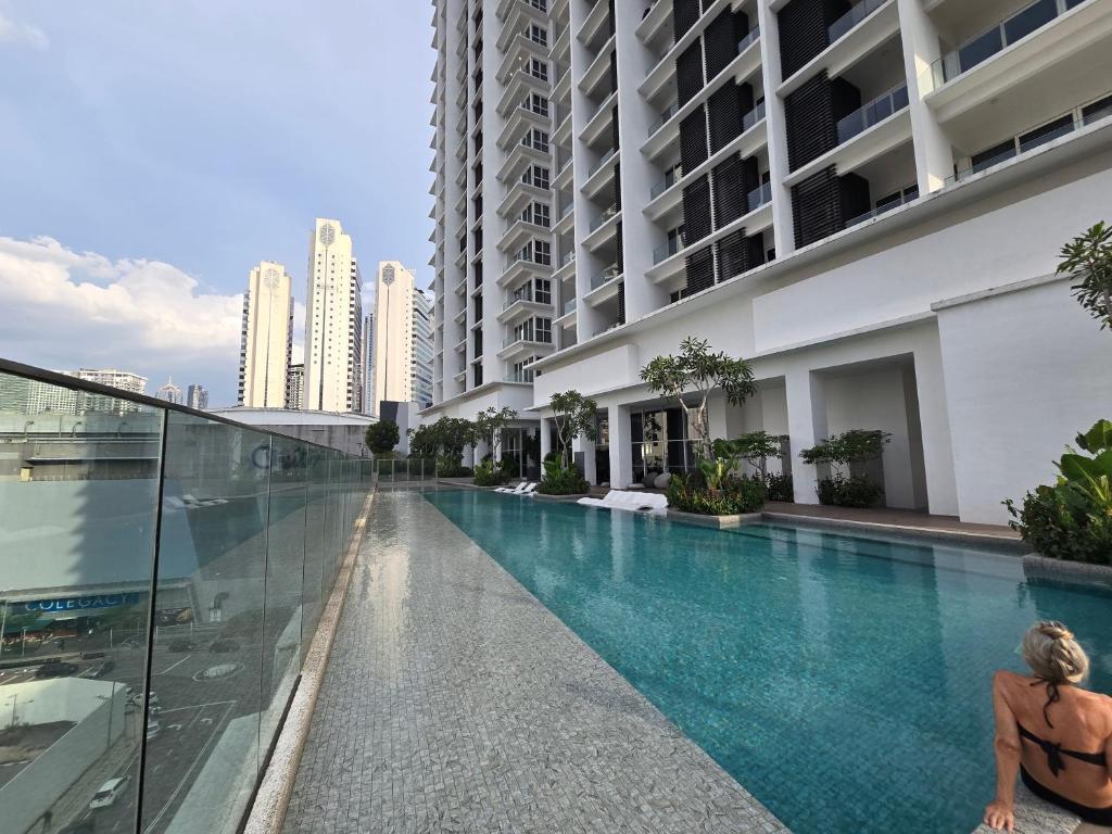 a woman sitting in a swimming pool next to a building at Quill Resort Suites Star House in Kuala Lumpur