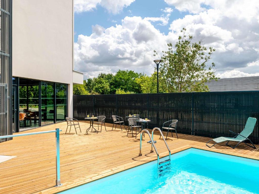 a patio with a pool and a table and chairs at ibis Bordeaux Nord Carbon Blanc in Carbon-Blanc
