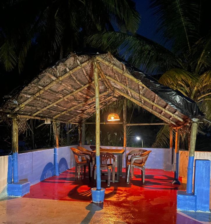 a restaurant with a table and chairs under a roof at Raaga on the Beach in Kannur