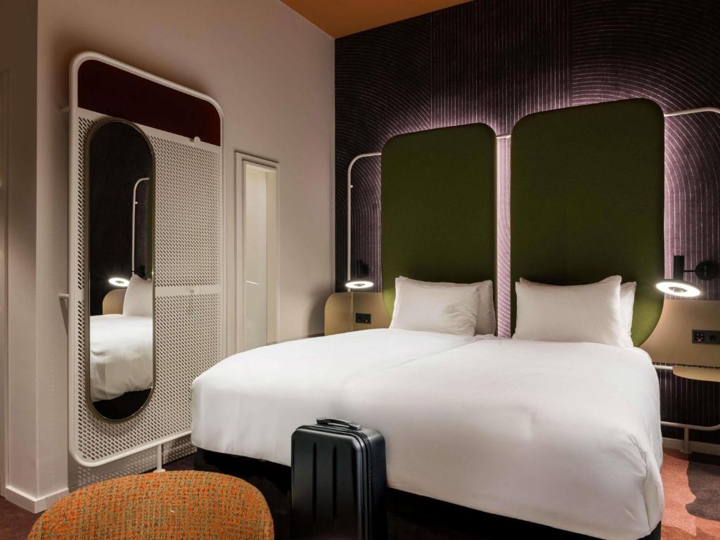 um quarto de hotel com uma cama grande e dois espelhos em You Hotel Budapest - Handwritten Collection em Budapeste