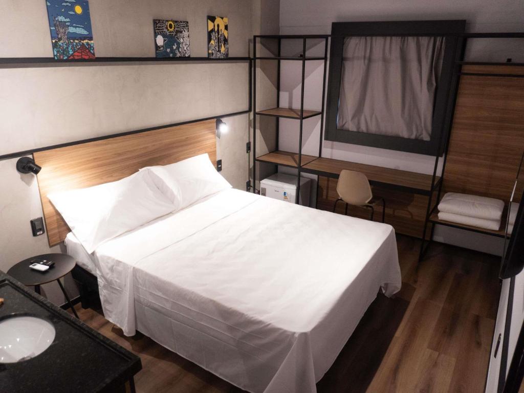 une chambre avec un lit blanc avec une tête de lit en bois dans l'établissement ibis Arcoverde, à Arcoverde