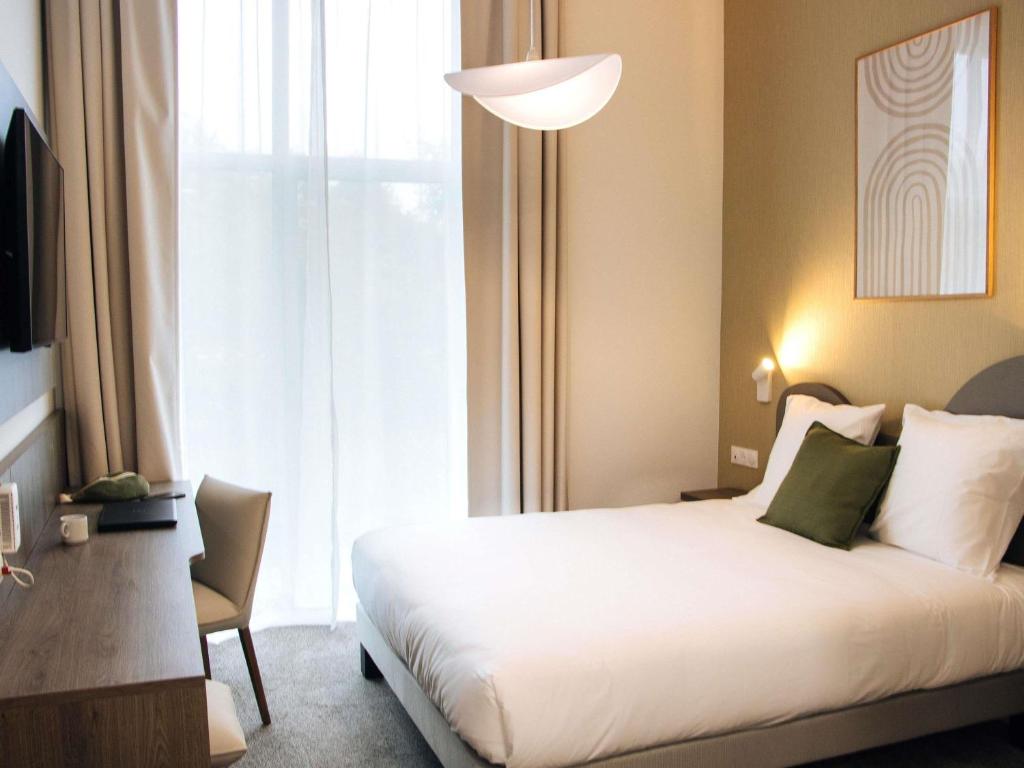 a hotel room with a bed and a window at Adagio Access Bordeaux Sud Pessac in Pessac