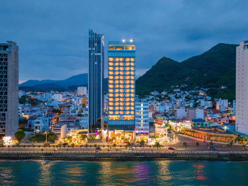 une ville avec un grand bâtiment face à l'eau dans l'établissement The Morning Glow - Handwritten Collection, à Nha Trang