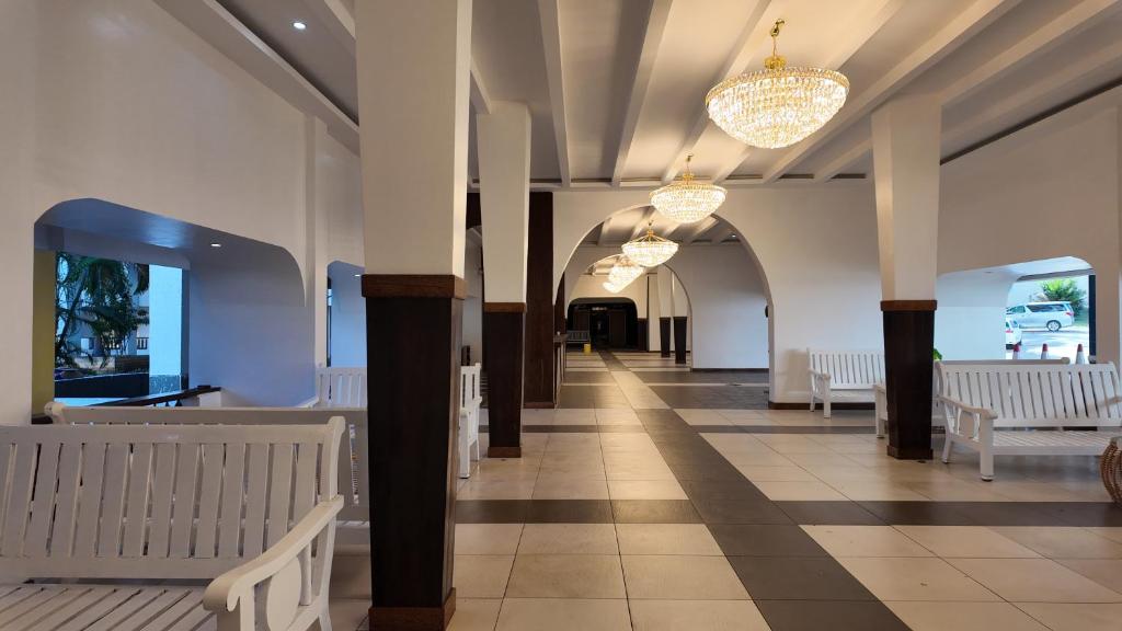Un pasillo con bancos blancos y candelabros en un edificio. en Diani Sands International Hotel, en Galu