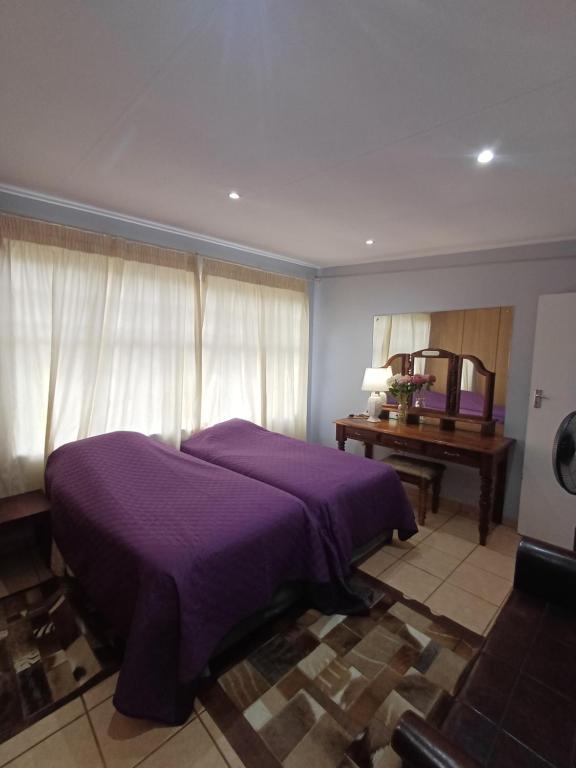 een slaapkamer met een paars bed en een tafel bij Bush and Birding Backpacker in Pretoria