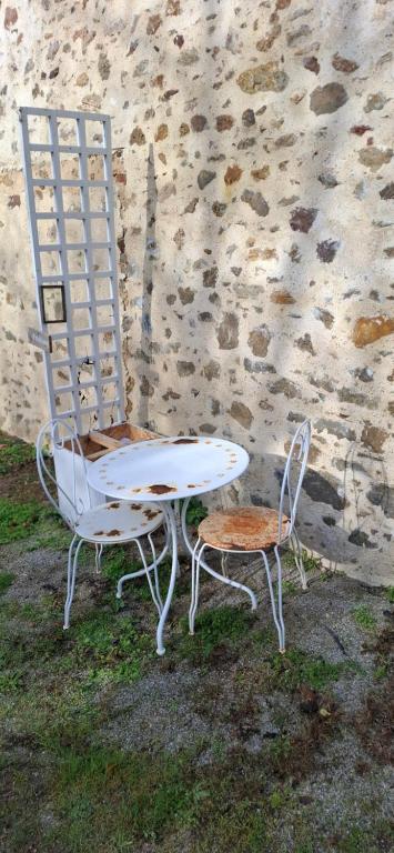 a table and two chairs sitting next to a stone wall at La Casita in Maisoncelles-du-Maine