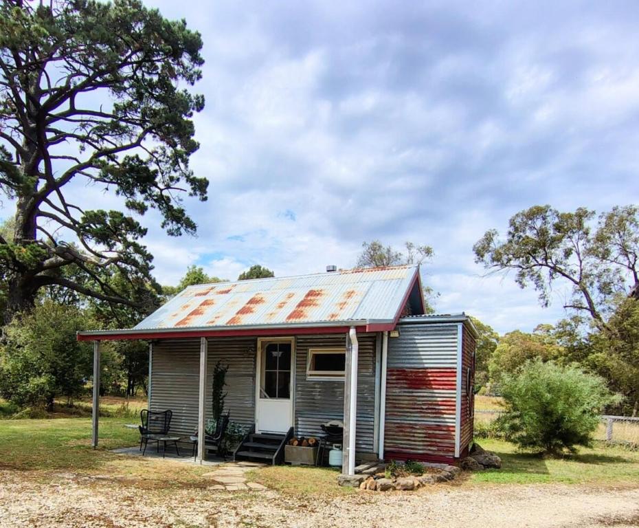 une petite maison avec un toit en étain au-dessus dans l'établissement Hanging Rock Farm Stay, à Newham